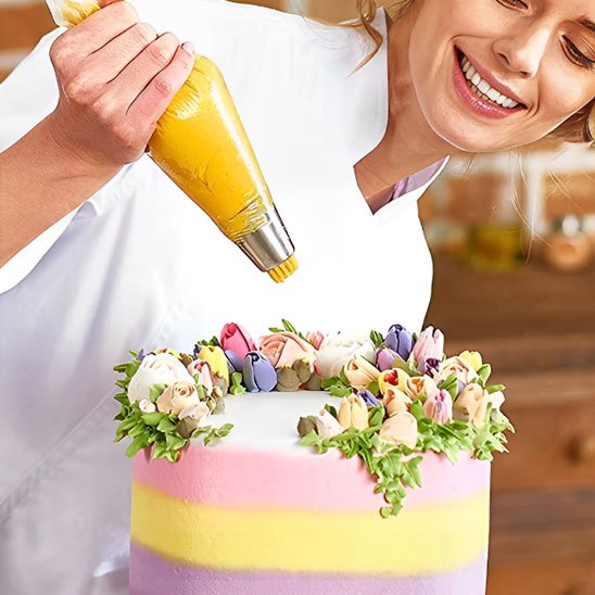 Décoration de gâteau par une femme avec Douille patisserie avec la poche à douille remplie de pâte jaune 
