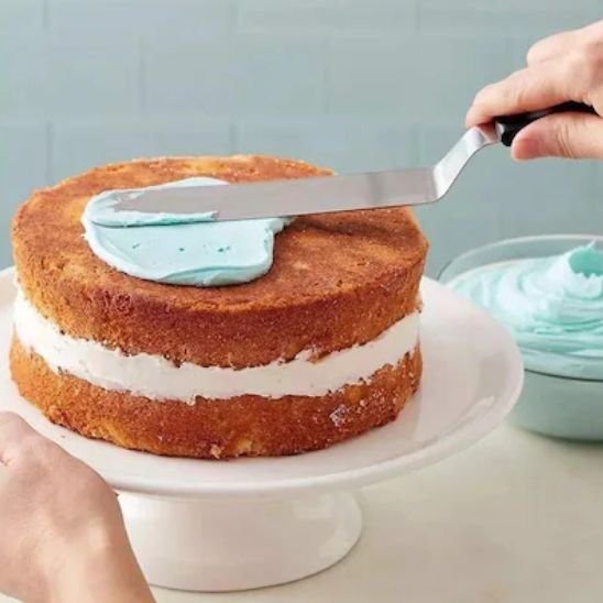 Étalage  de crème pâtissière blue sur les cupcakes  avec une Spatule 