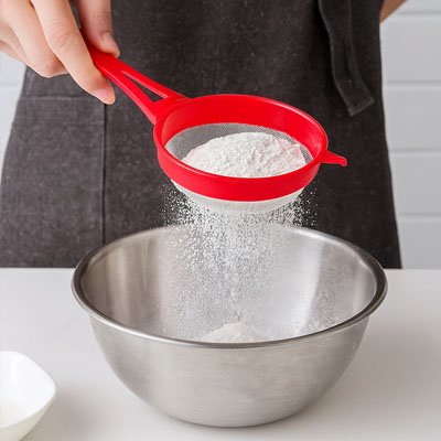 Tamisage sucre glace  avec Passoire plastique rouge