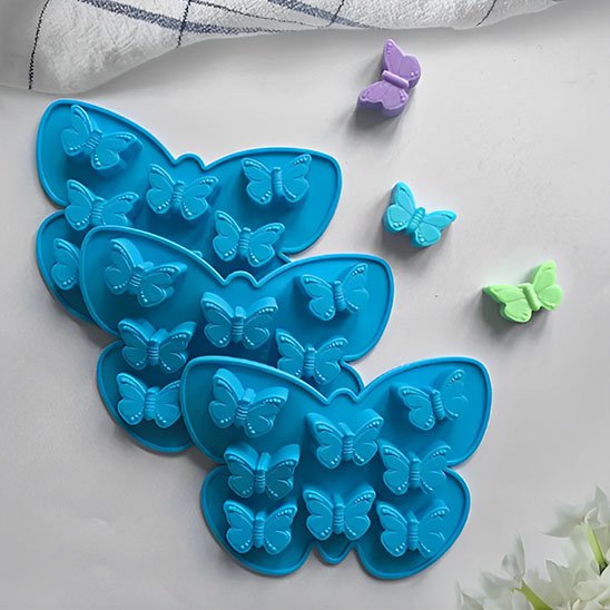  Trois Moules à gateau bleu-foncé présentés avec trois petits biscuits  en forme de papillon